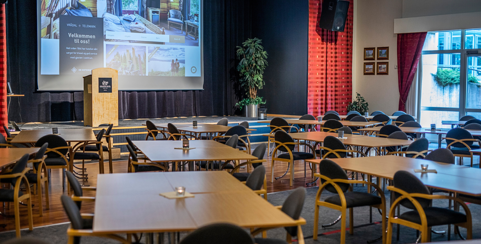 a room with tables and chairs and a projector screen