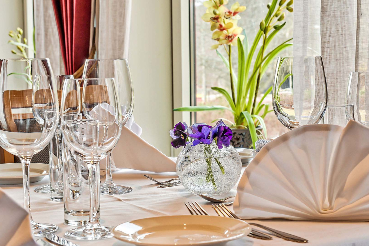 a table set with glasses and a vase of flowers