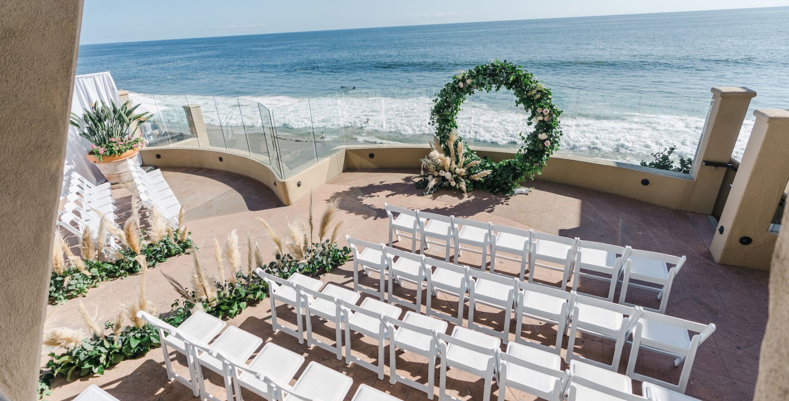 a wedding ceremony set up with chairs and a wreath of flowers