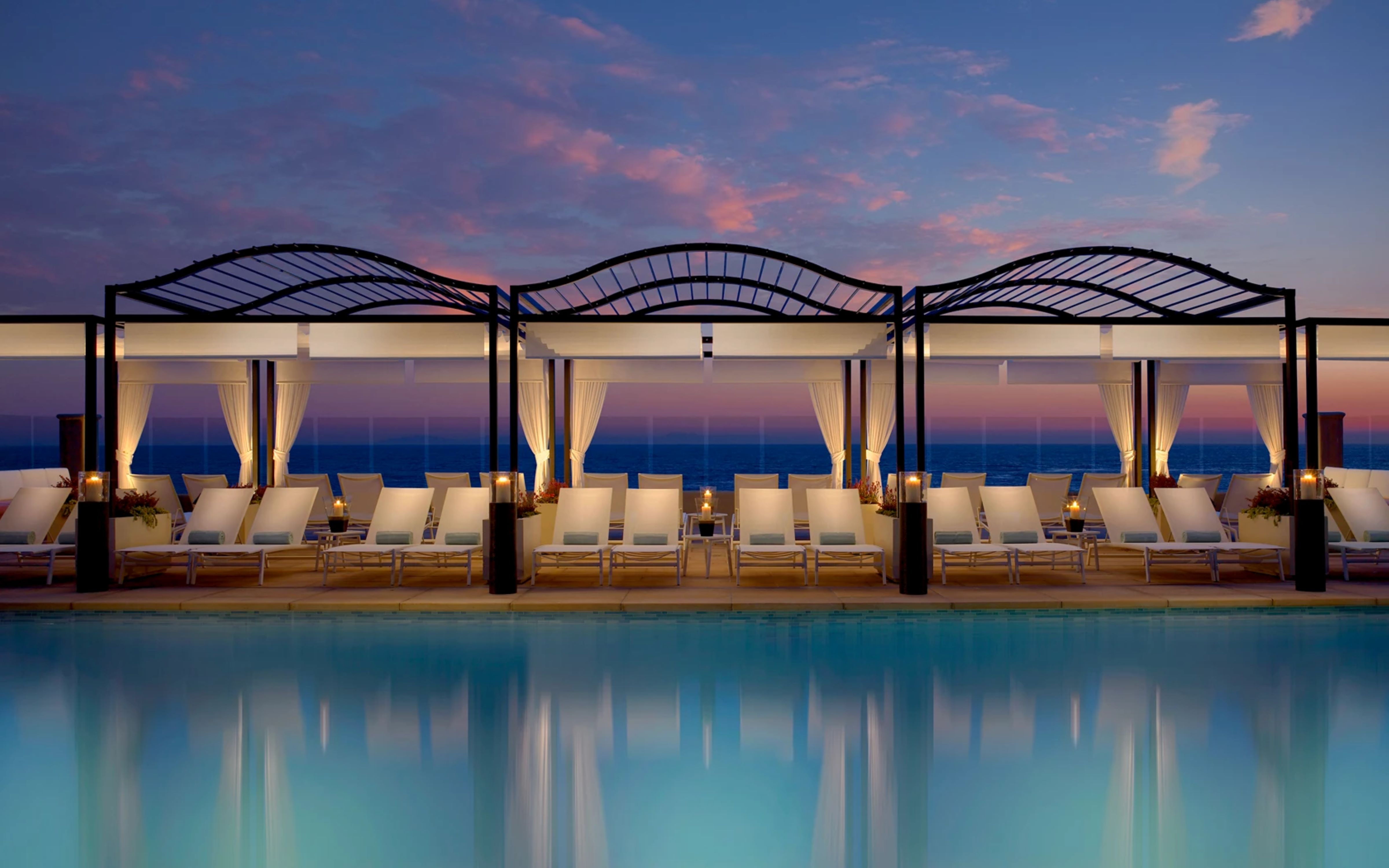 a pool with lounge chairs and a large body of water