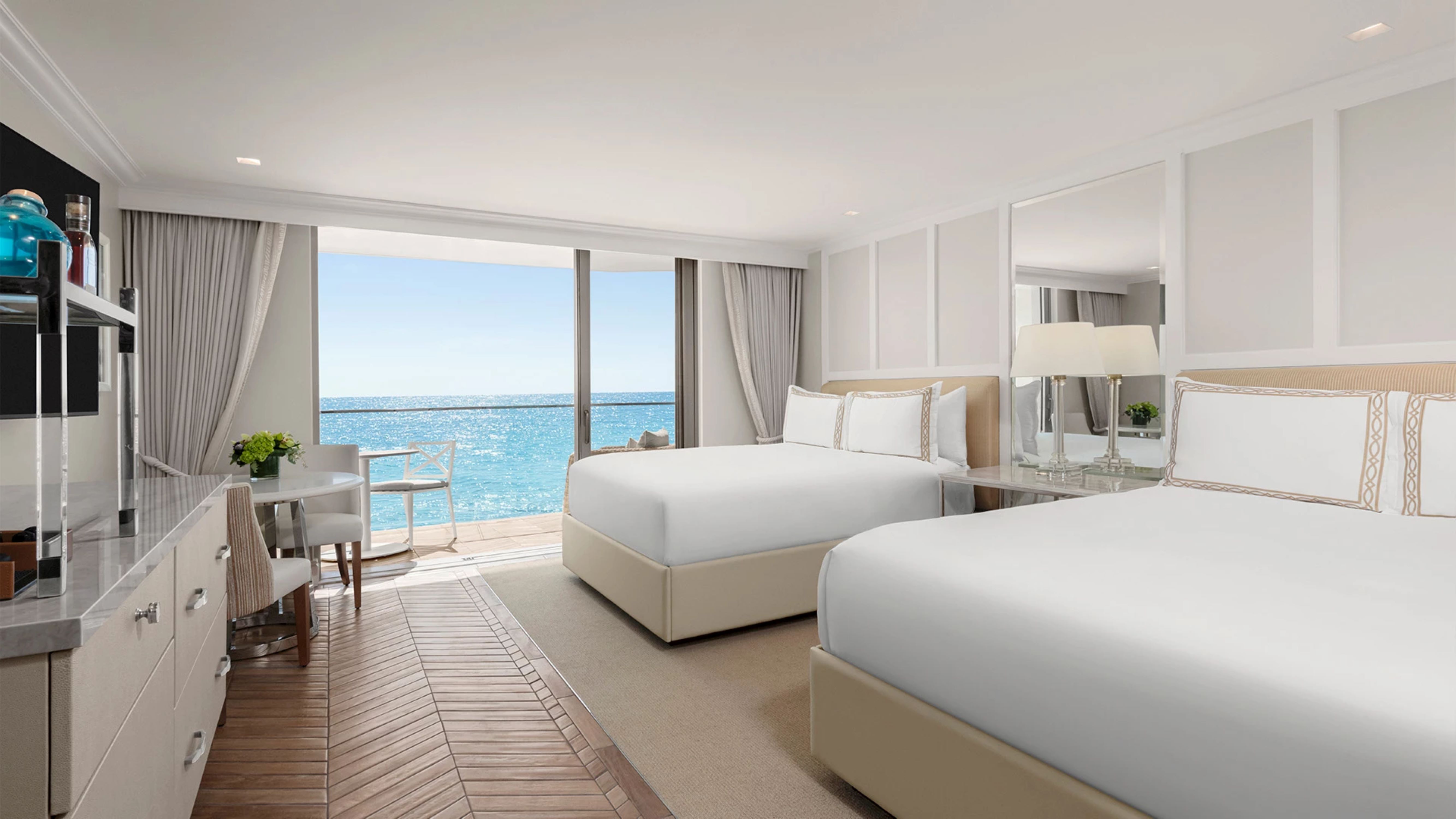 a room with two beds and a view of the ocean