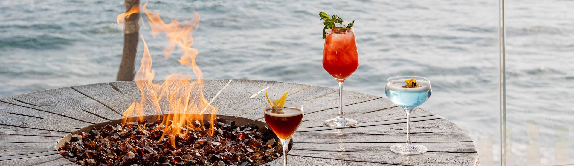a couple of glasses of drinks on a table next to a fire pit