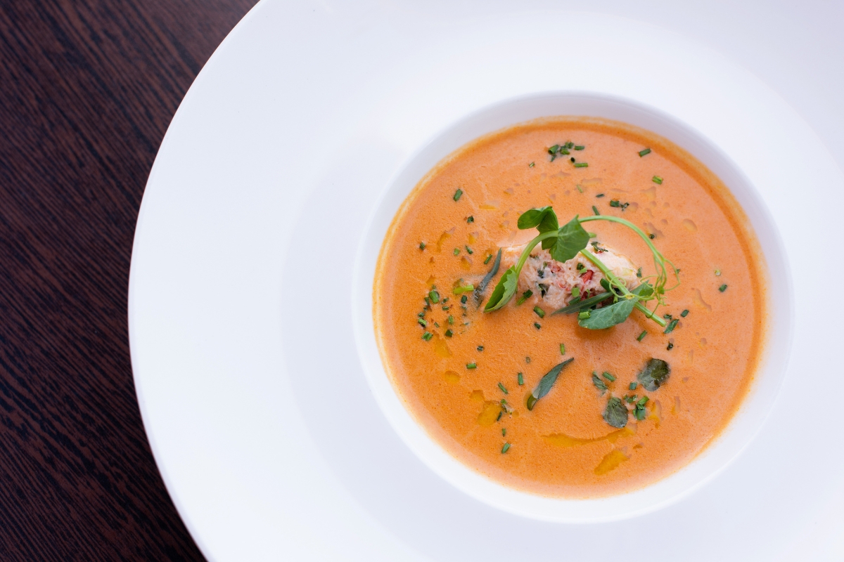 a bowl of soup with a piece of meat and herbs