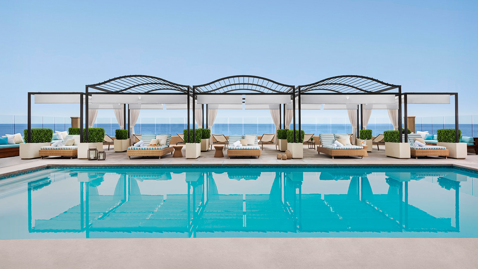 a pool with lounge chairs and a large body of water