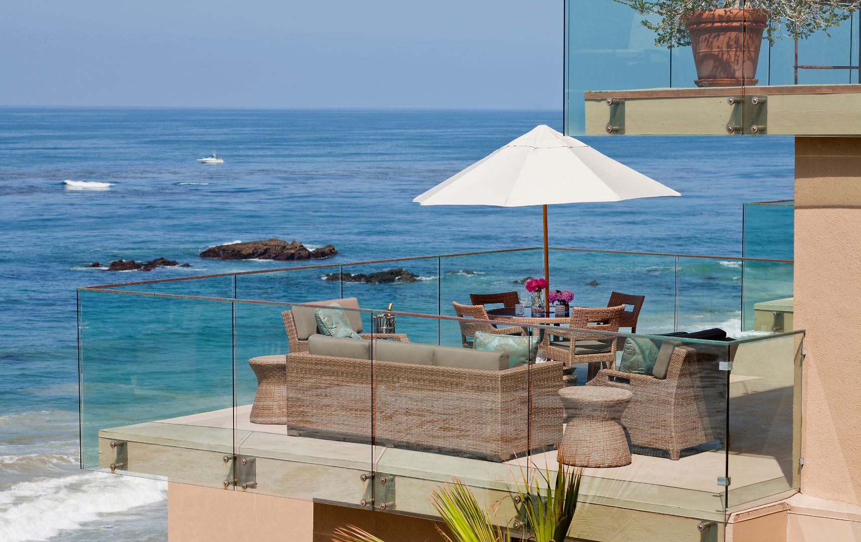 a patio with a table and umbrella overlooking the ocean