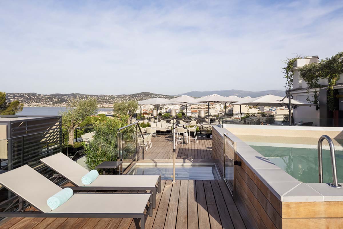 a deck with chairs and a pool overlooking a city