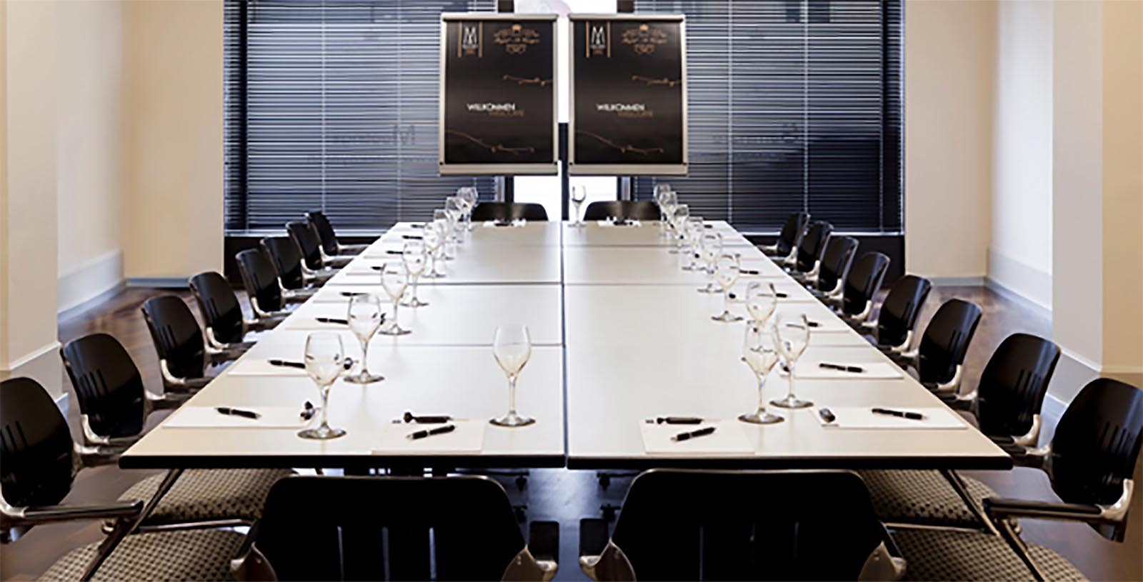 a long conference table with wine glasses and pens