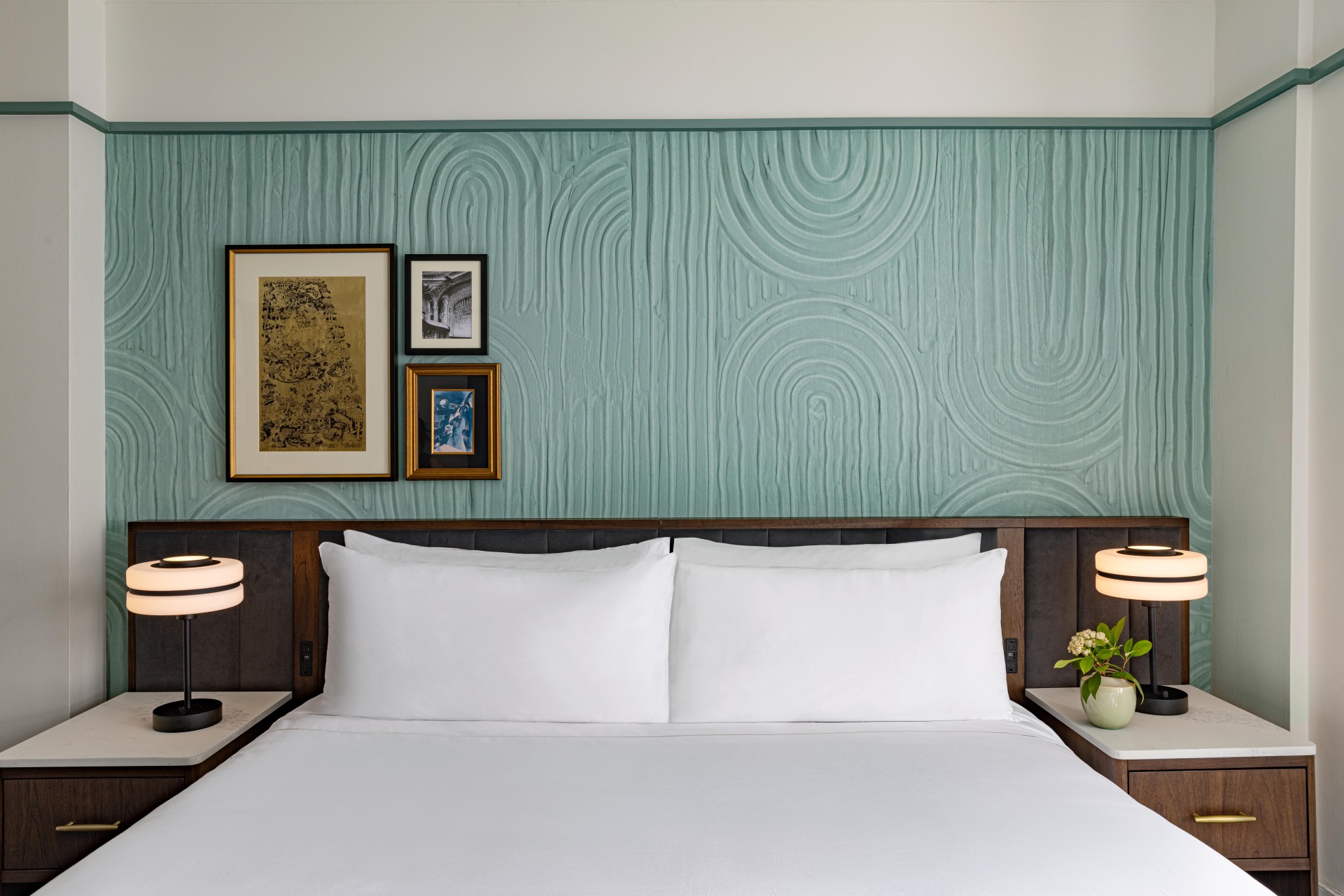 a bed with white sheets and a lamp on a table