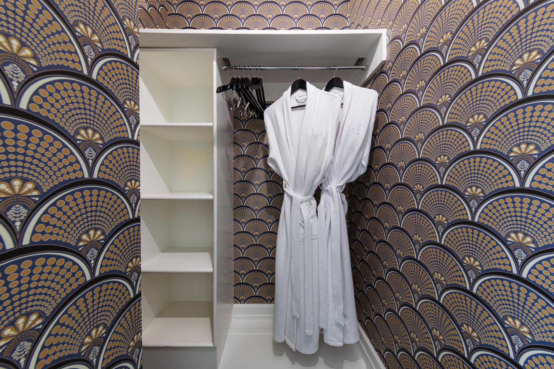 a closet with white bathrobes and shelves