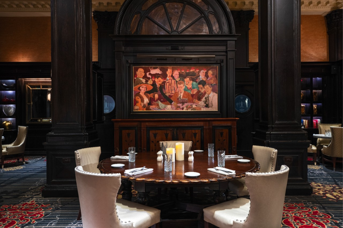 a table with white chairs and a painting on the wall