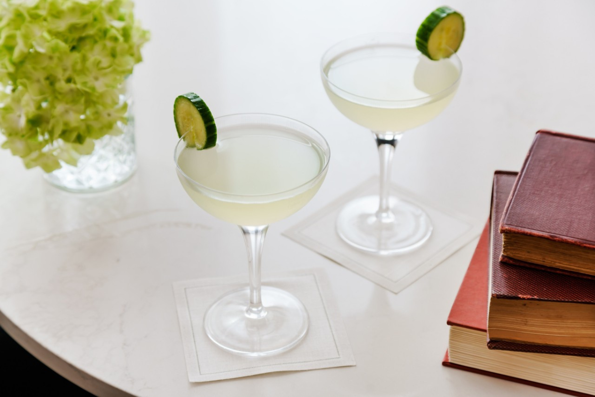 two glasses of liquid with cucumber slices on top of each other