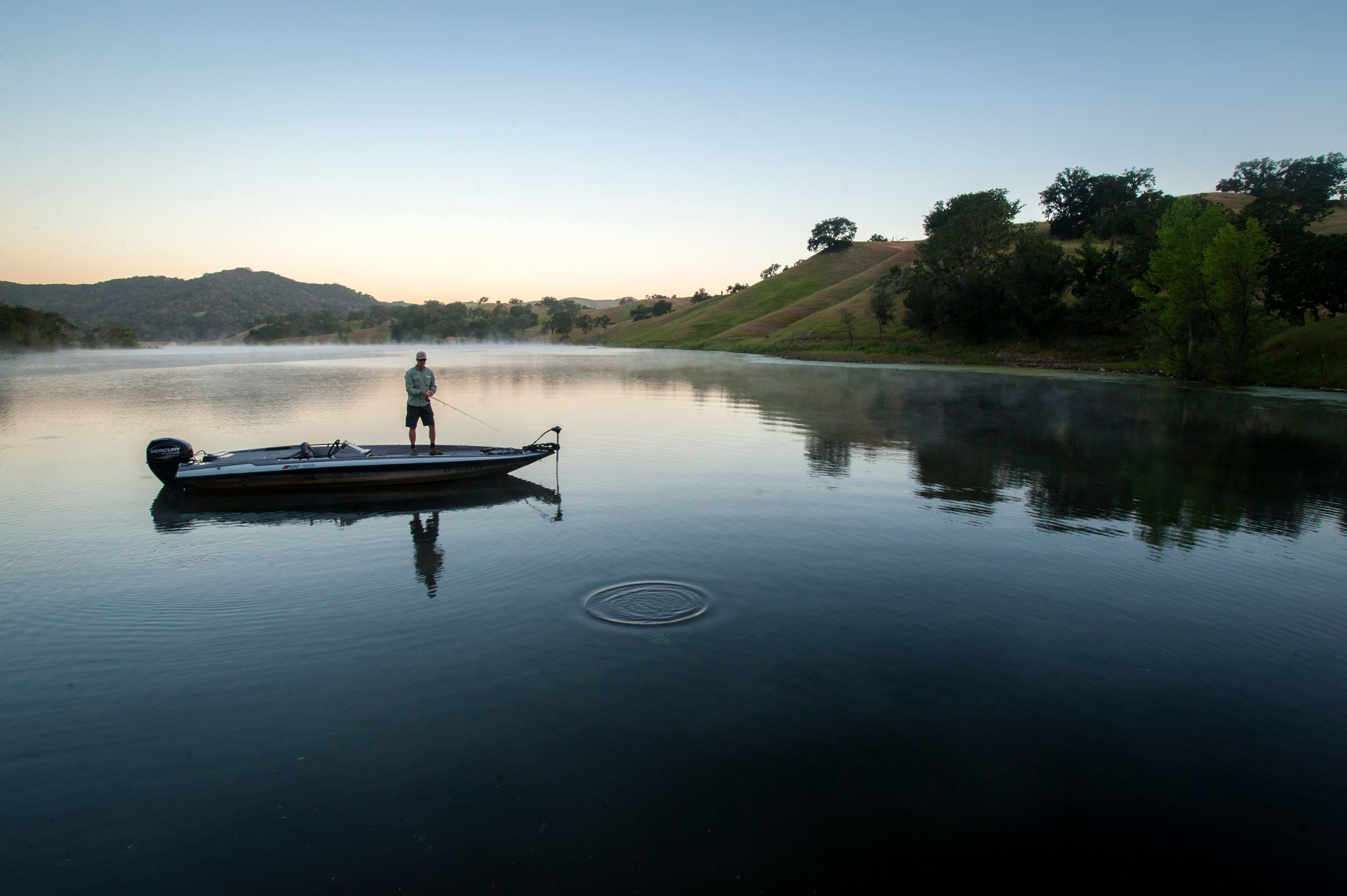a man fishing on a boat on a lake