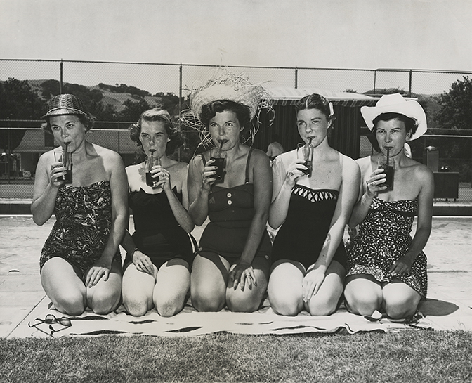 a group of women sitting on a blanket drinking from drinks