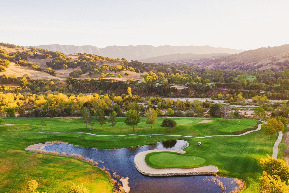 a golf course with a river and trees