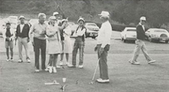 a group of people standing around a golf course