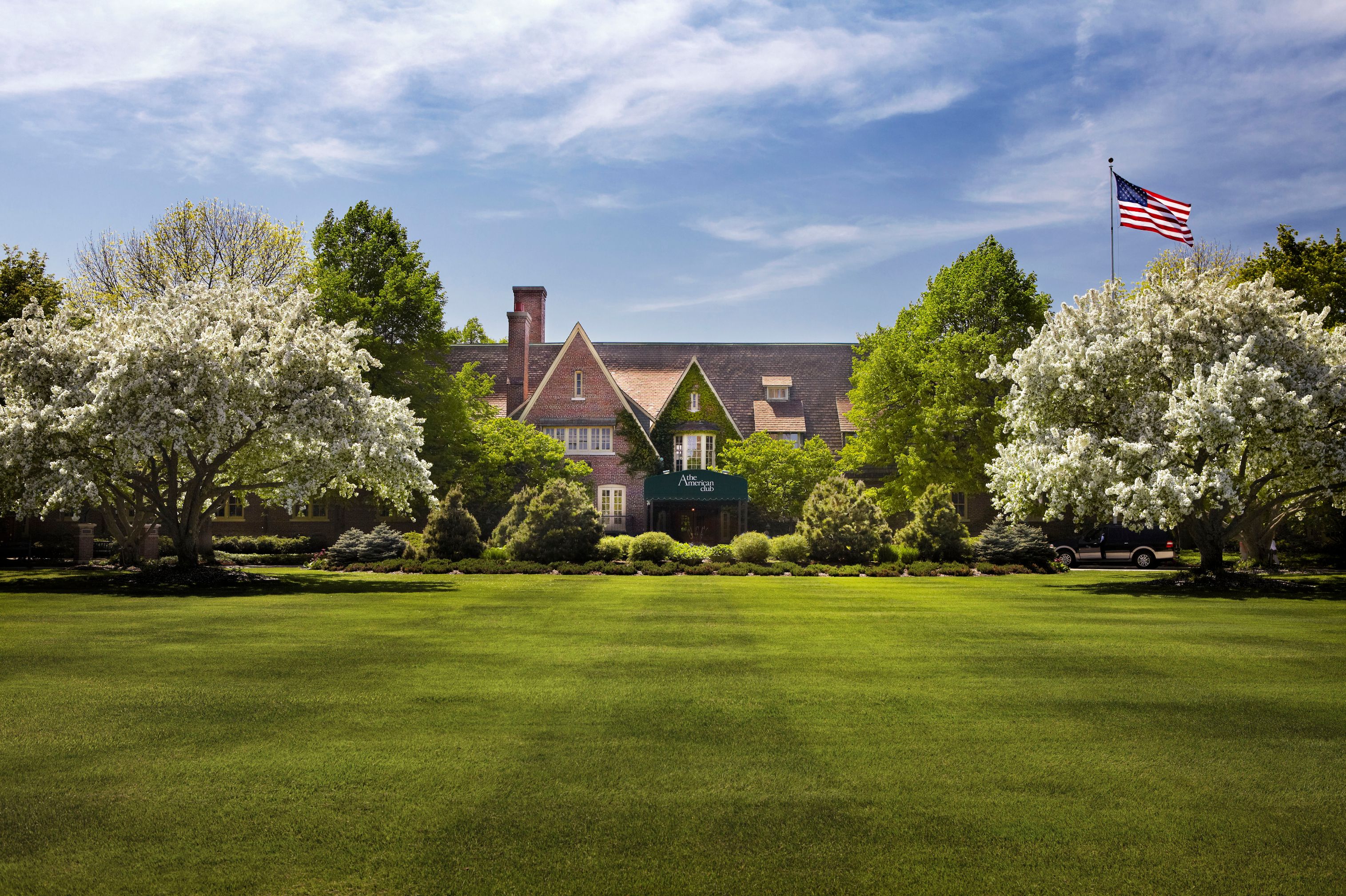 a lawn with trees and a building in the background
