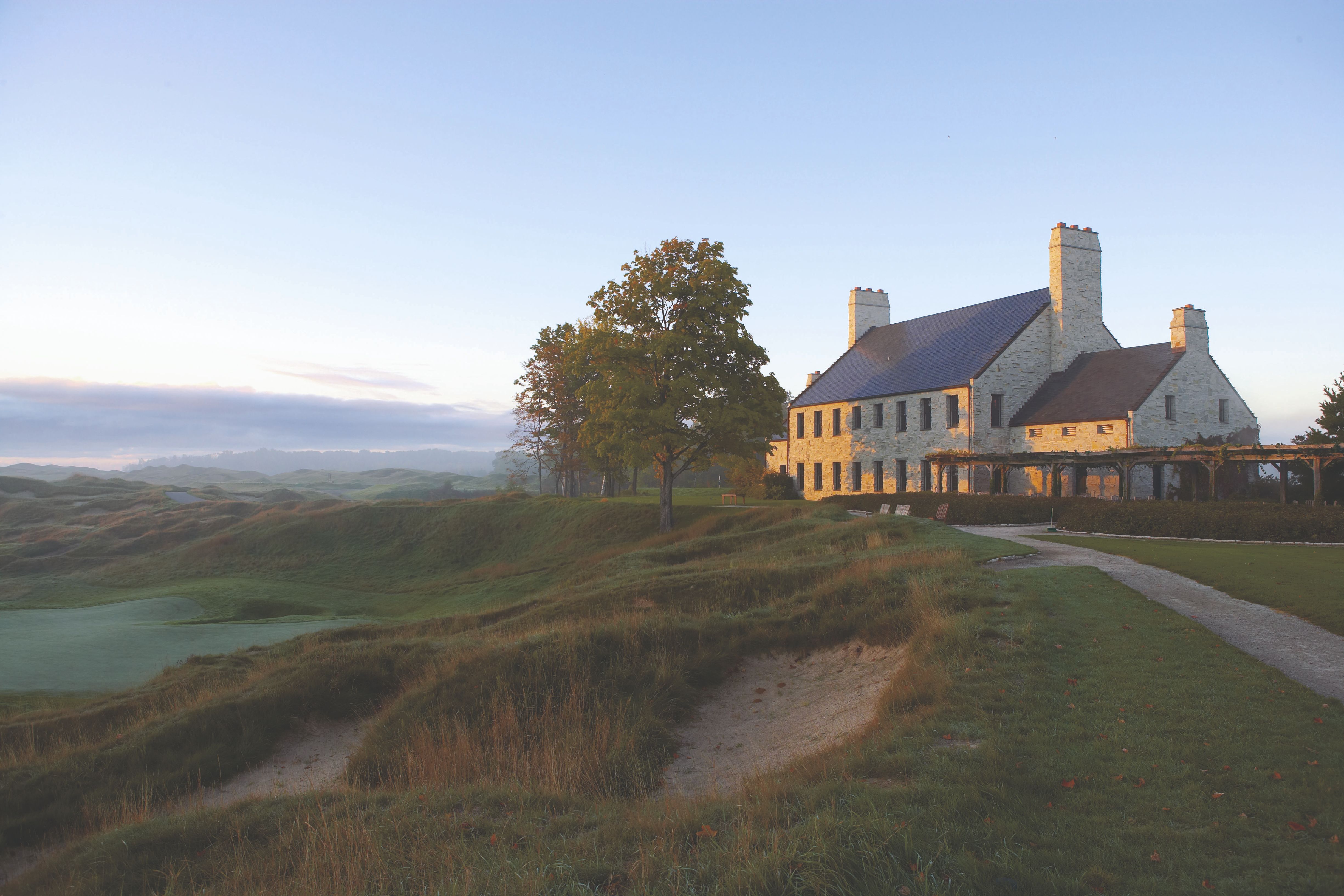 a large stone building with a path leading to a golf course