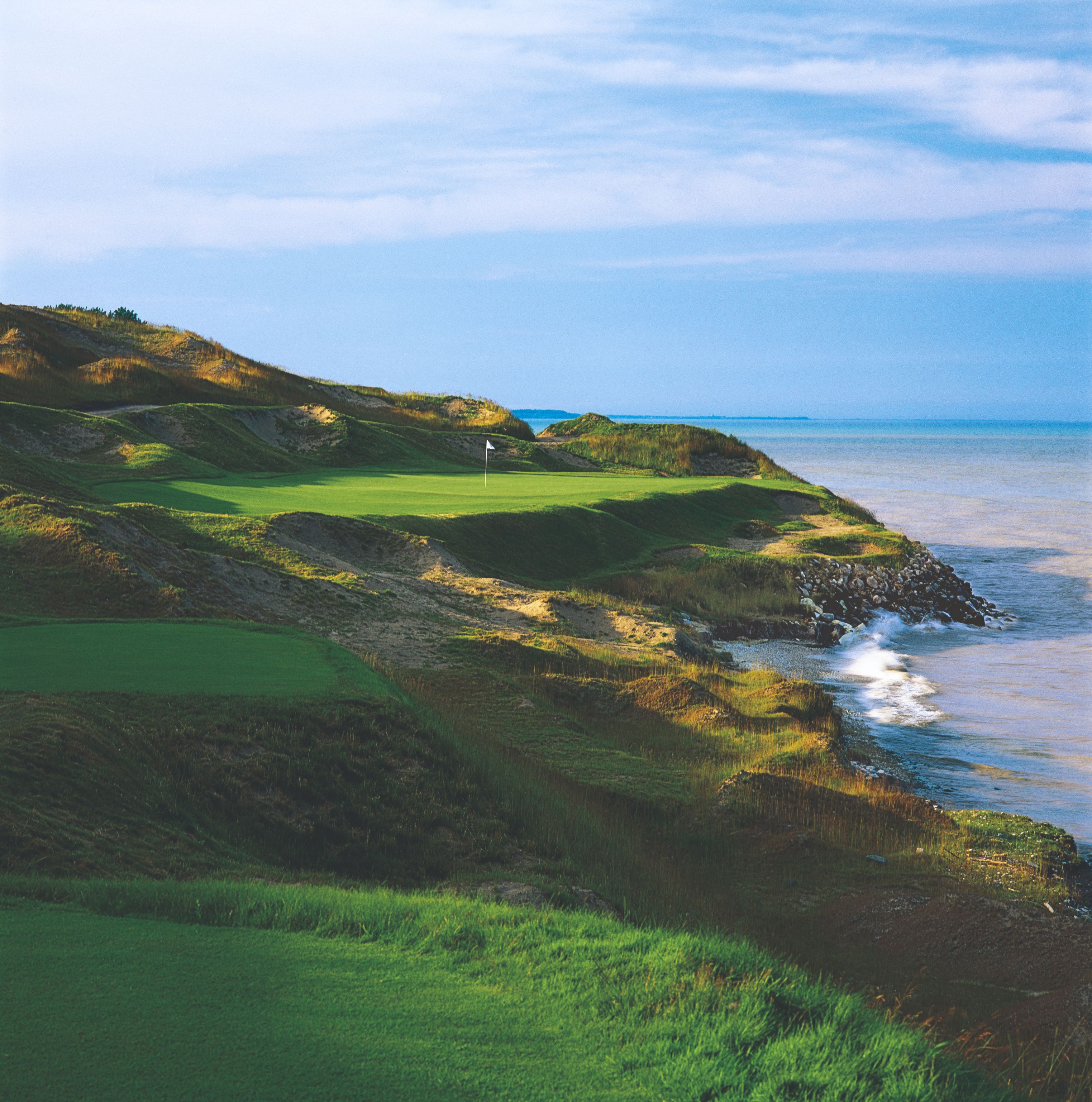 a golf course on a rocky hillside by the water