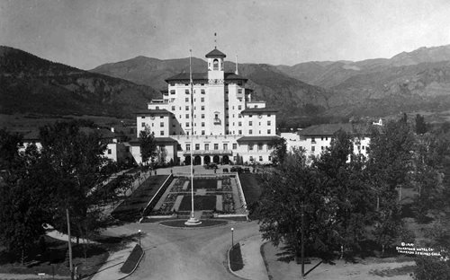 a large white building with a garden and trees
