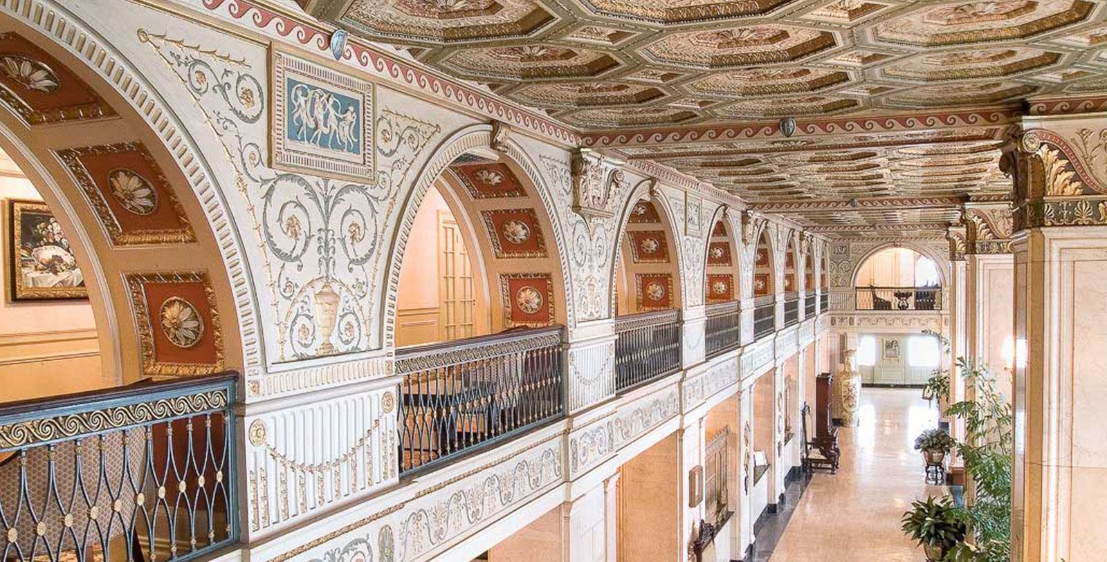 a long hallway with ornate walls and a balcony