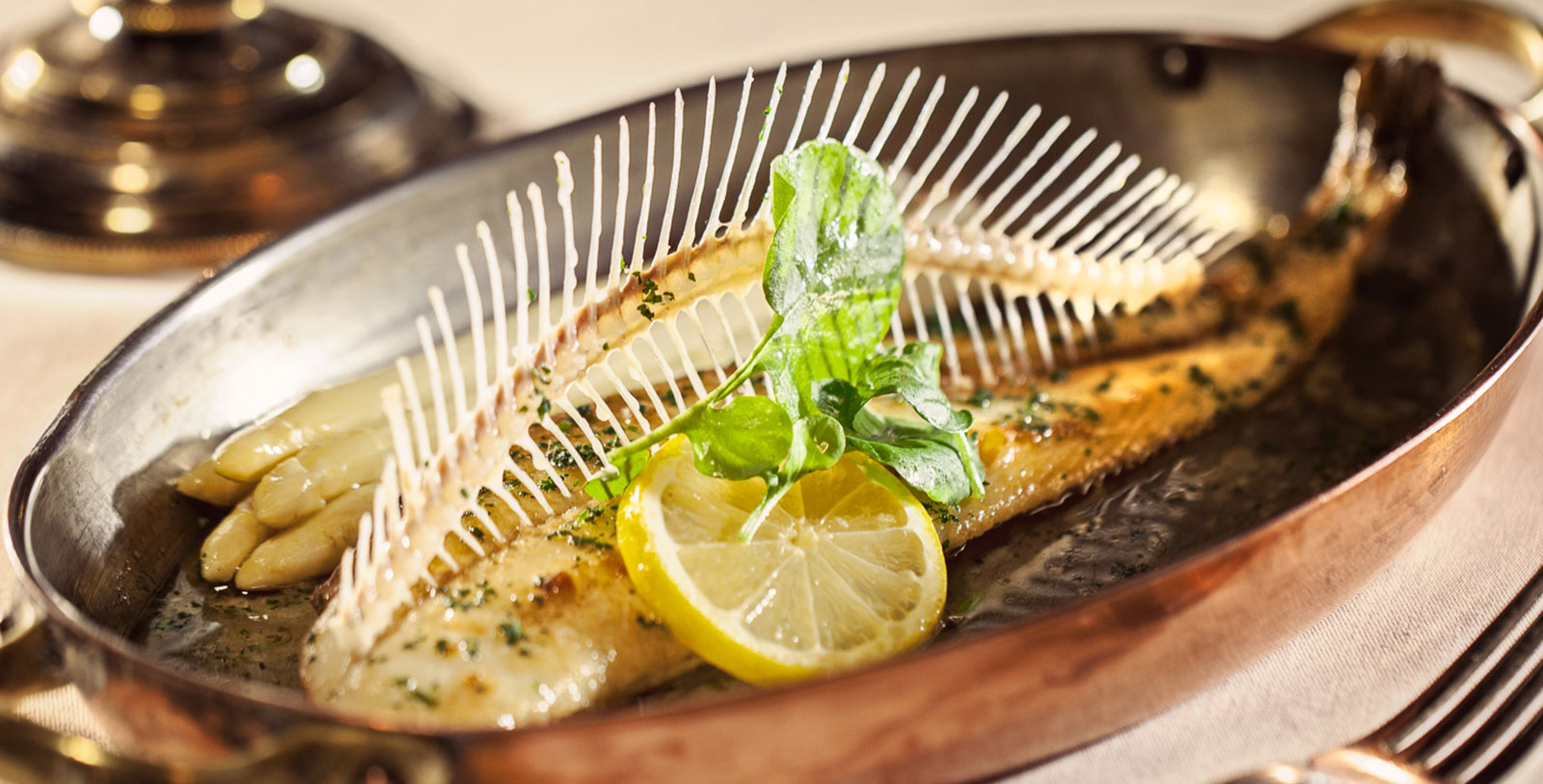 a fish with lemon slices and herbs in a pan