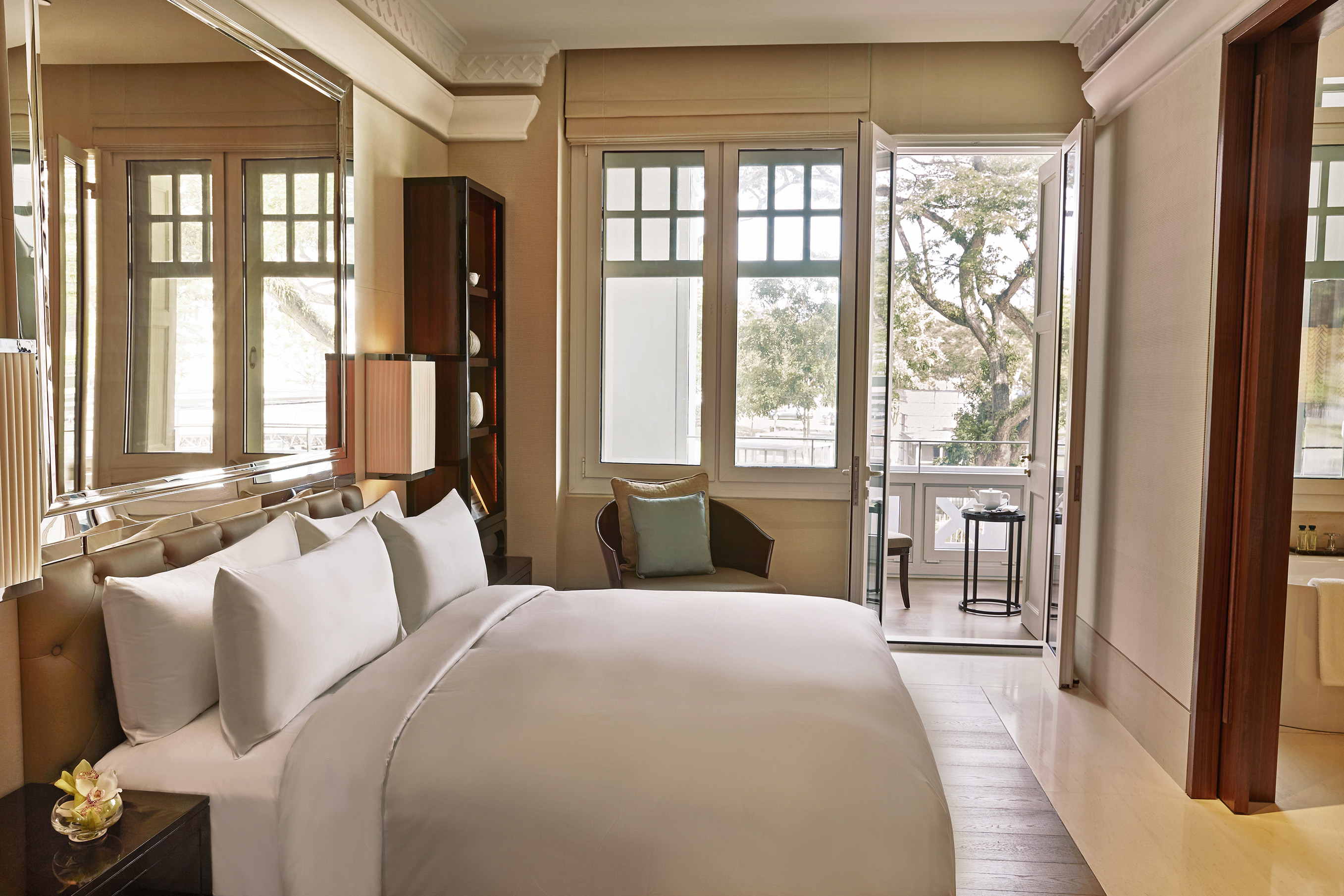 a bed with white sheets and a chair in a room with a door open