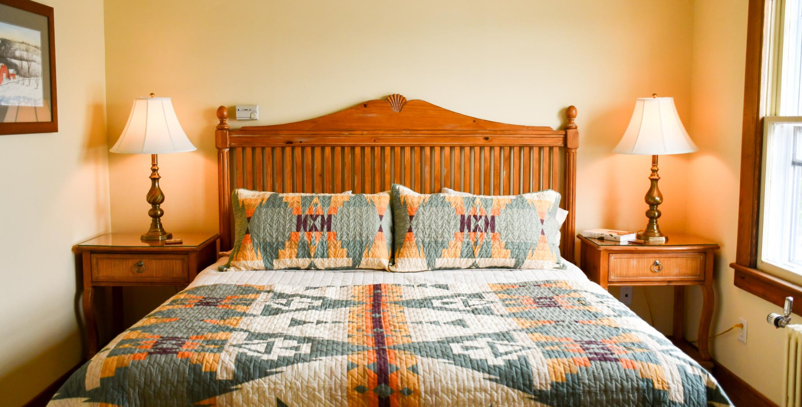 a bed with a colorful quilt and a lamp on the side of it