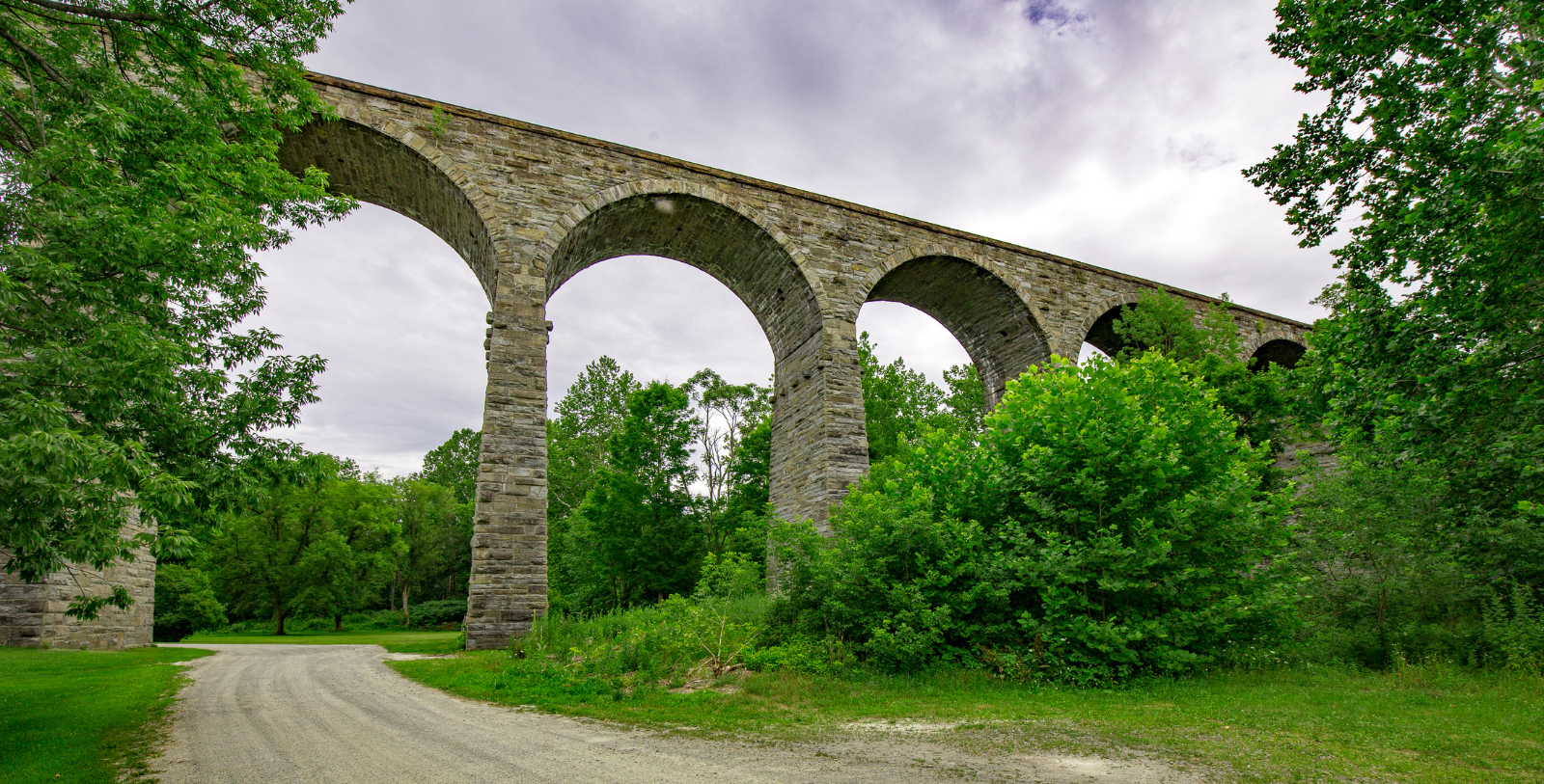 a stone bridge with arches and trees