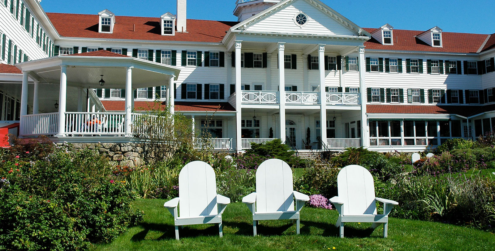 a white lawn chairs in front of a large white house