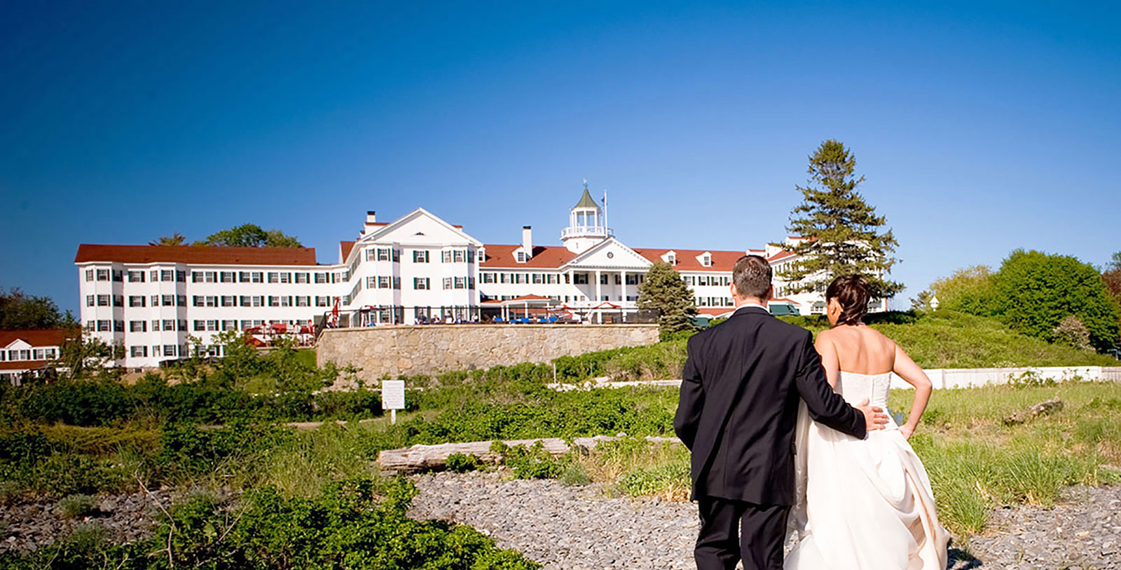 a bride and groom walking in front of a large white building