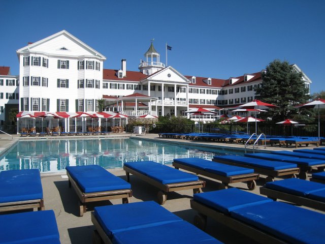 a pool and lounge chairs in front of a hotel