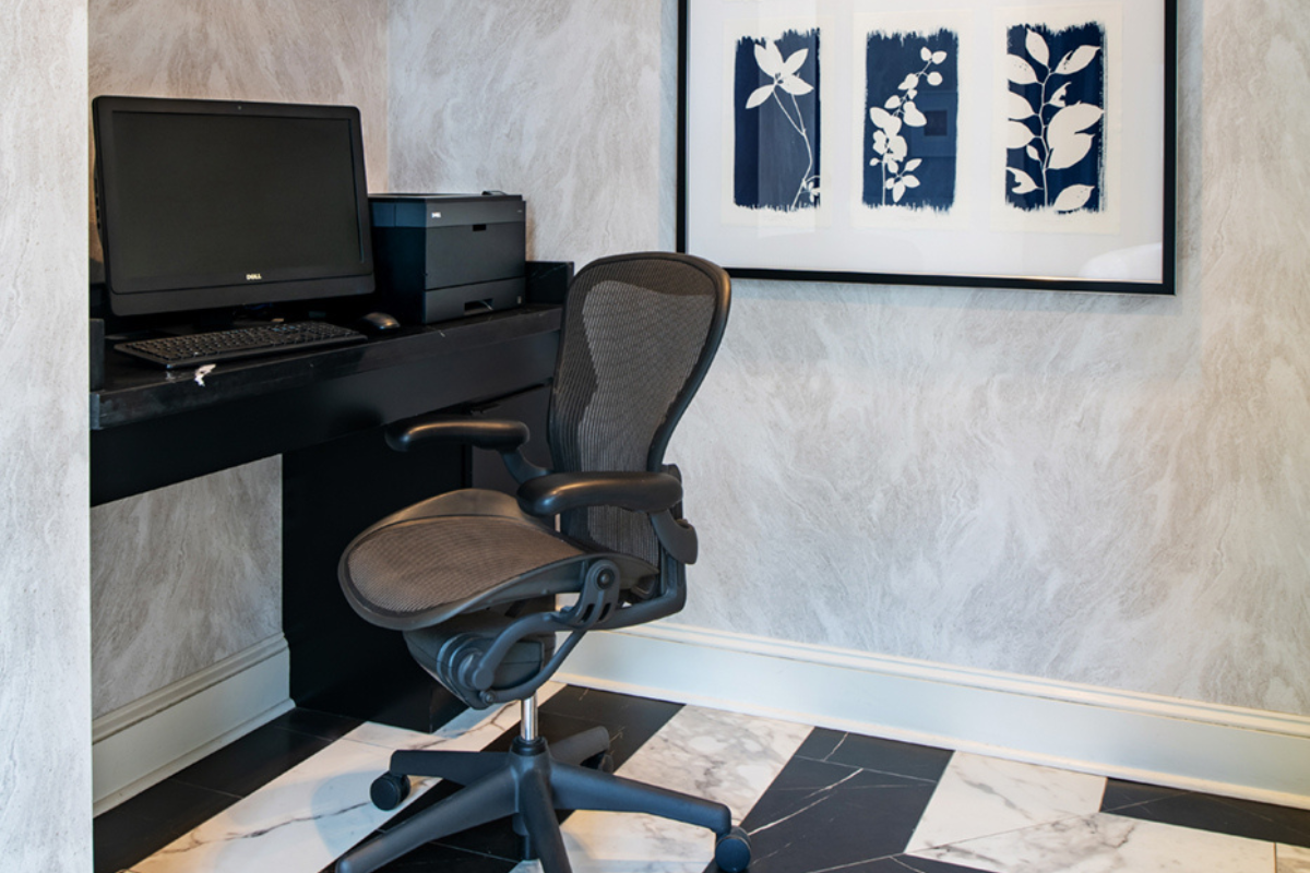a chair in a room with a computer and a picture on the wall