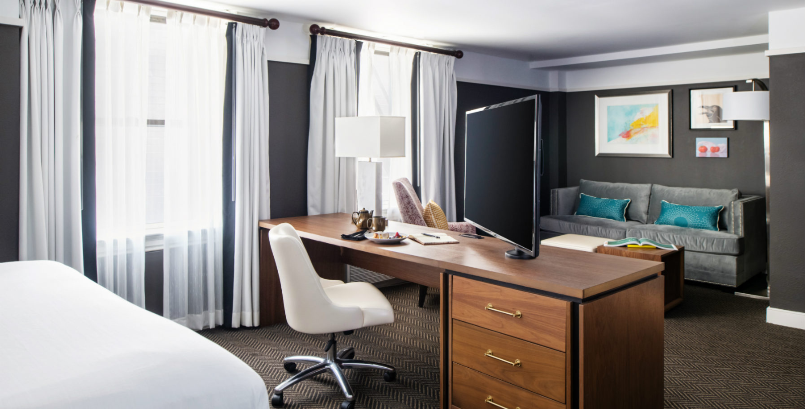 a desk with a computer and a chair in a hotel room