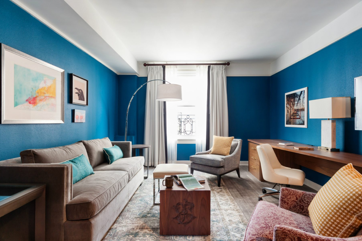 a living room with a blue wall and a couch and a desk