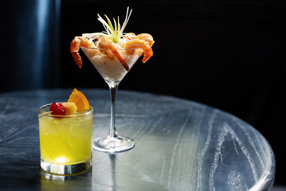 a cocktail with shrimp and a drink on a table
