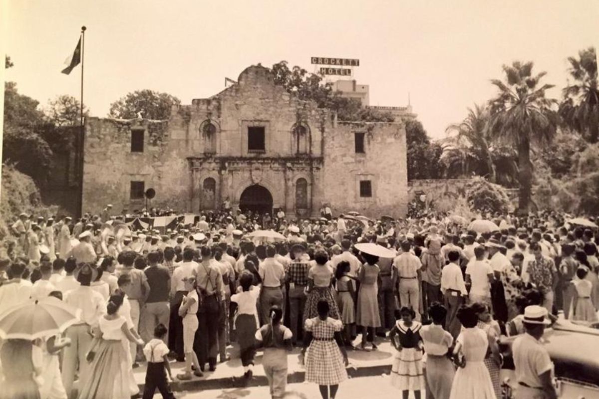 a group of people standing in front of Alamo Mission in San Antonio