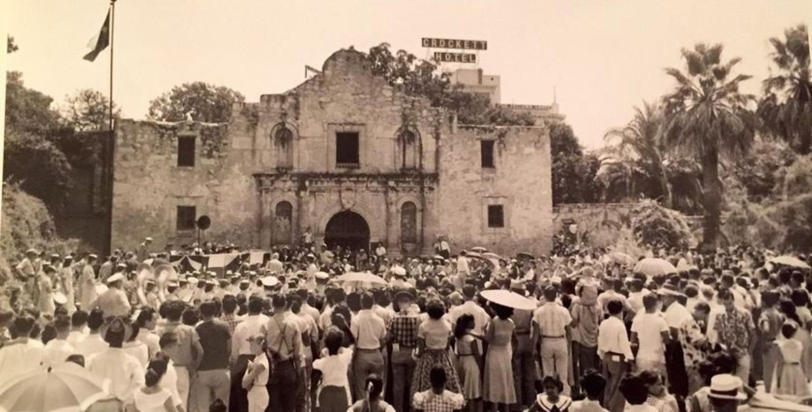 a group of people standing in front of a stone building with Alamo Mission in San Antonio in the background