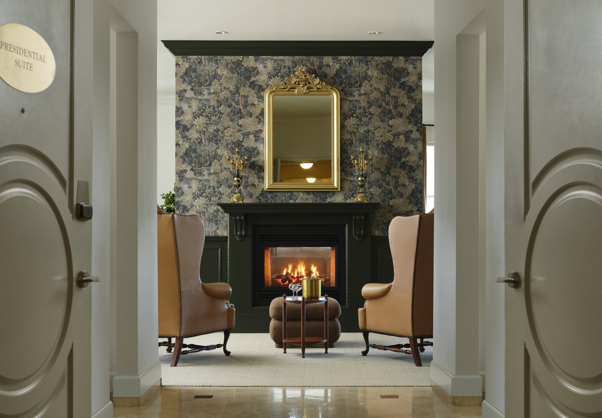 a fireplace in a room with chairs and a mirror
