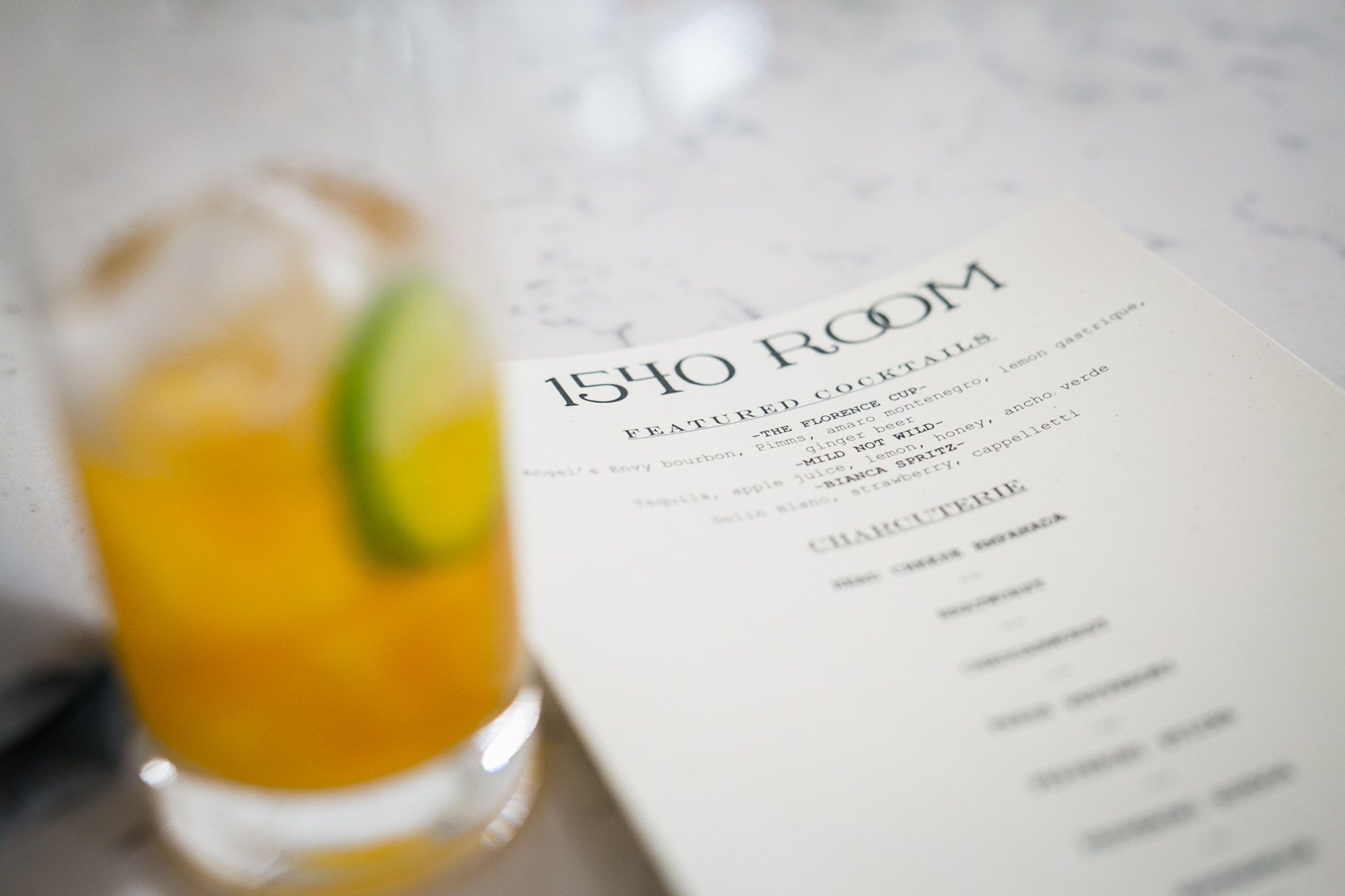 a glass of orange liquid next to a menu