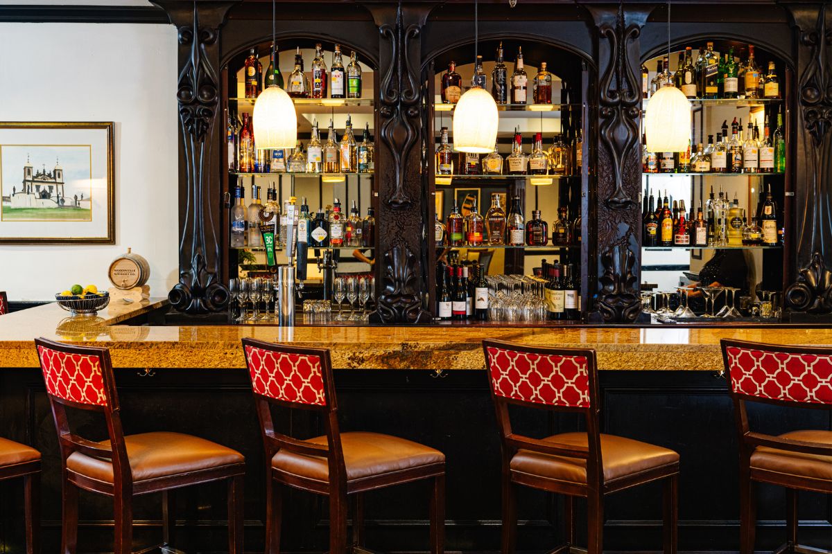 a bar with chairs and bottles of alcohol
