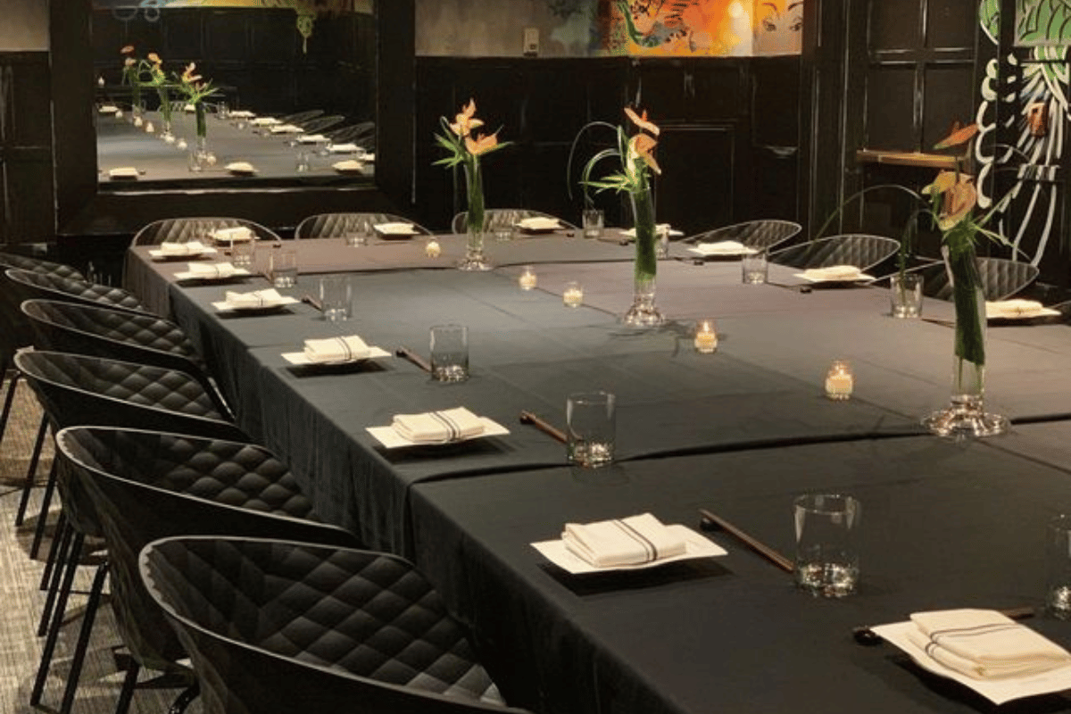 a long table with black tablecloths and black chairs