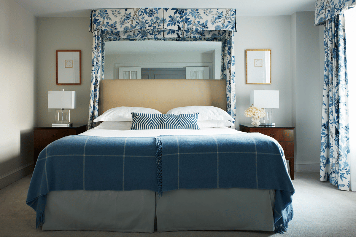 a bed with a blue blanket and a mirror above it
