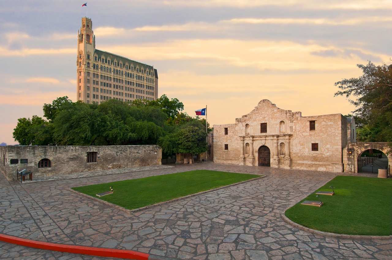 a stone courtyard with a stone building and a tall building