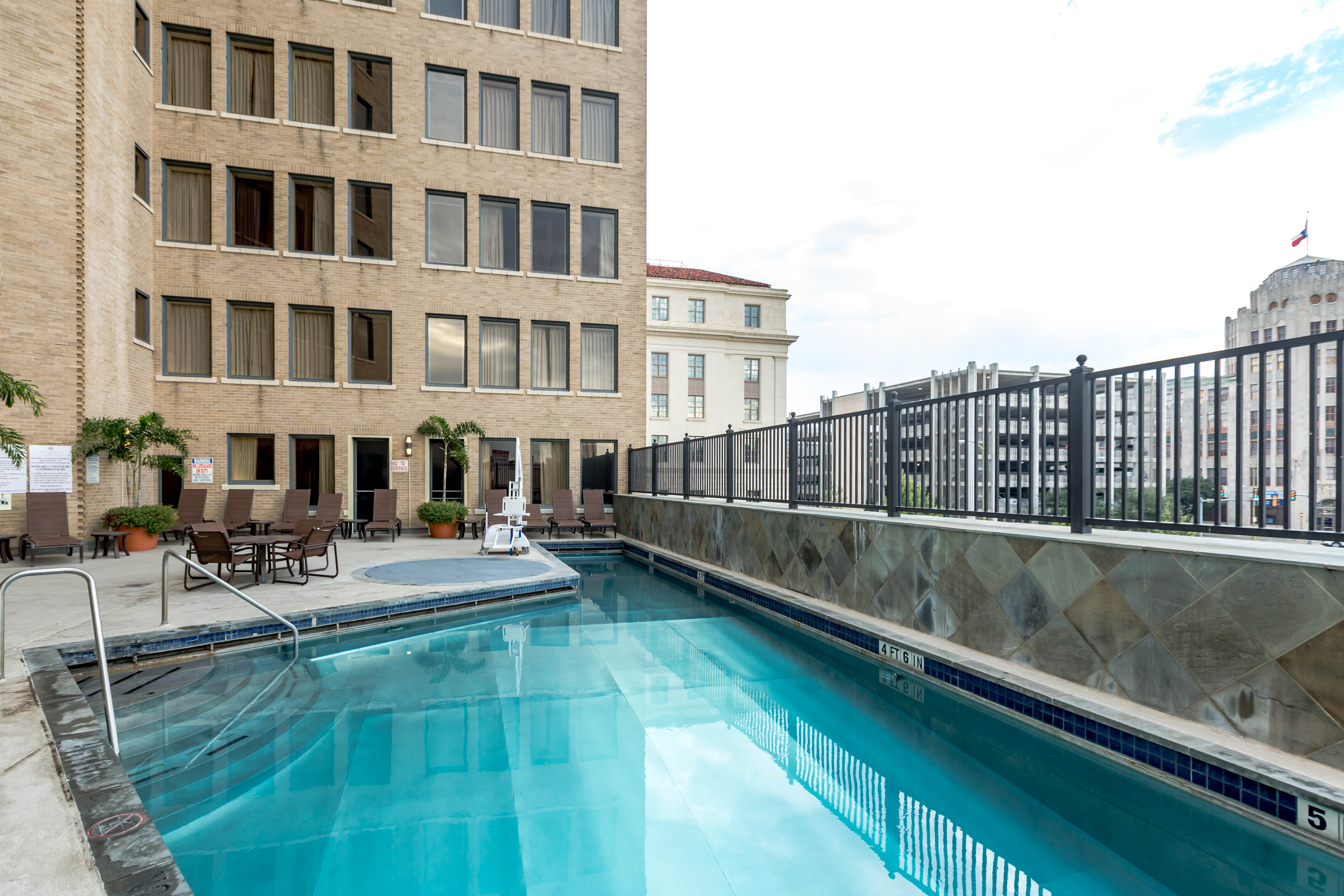 a swimming pool with chairs and a building in the background