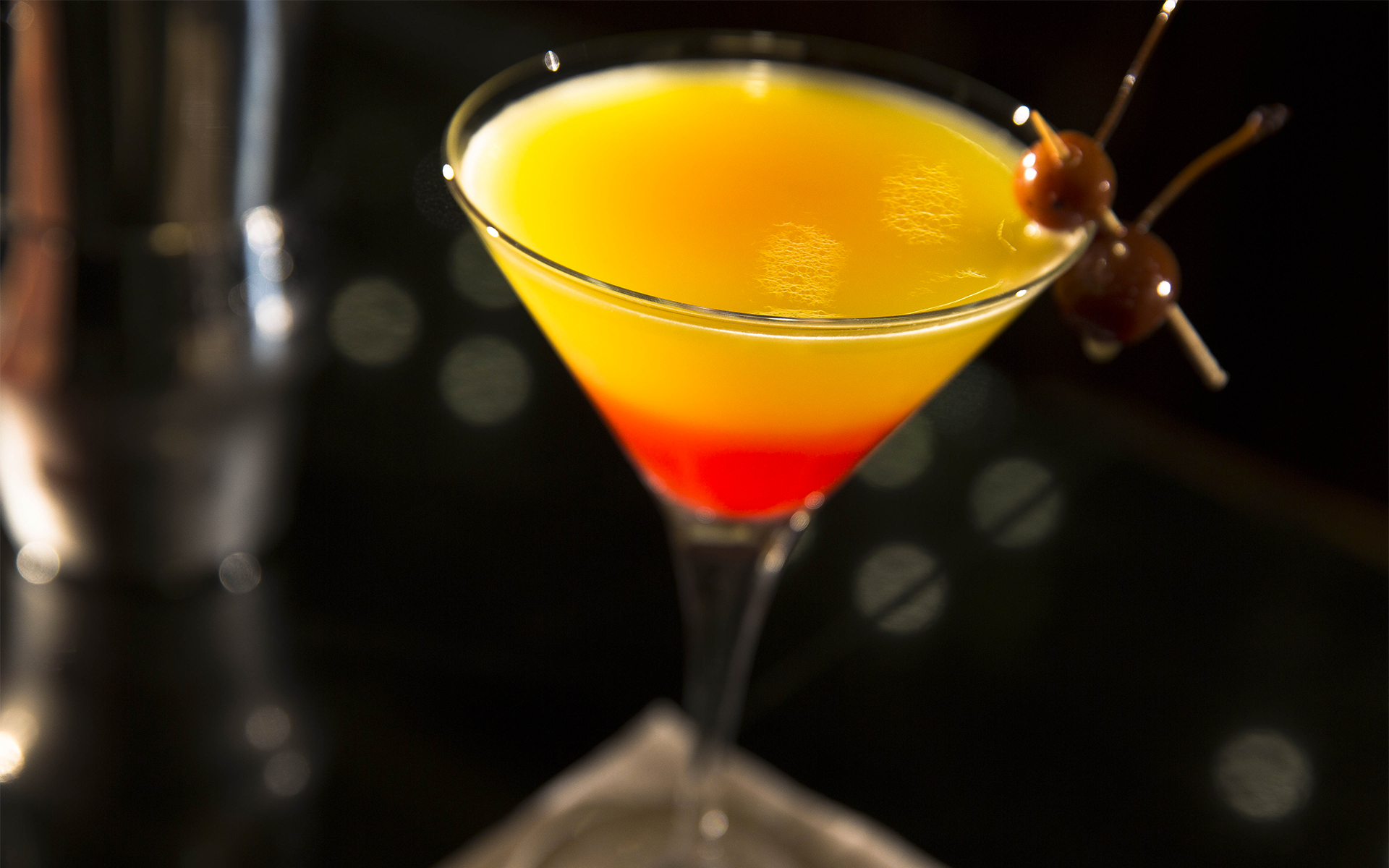 a yellow and red drink in a martini glass