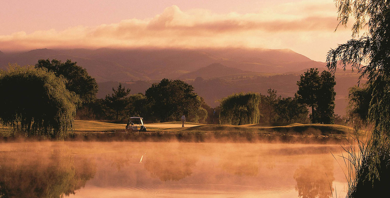 a golf course with fog and trees