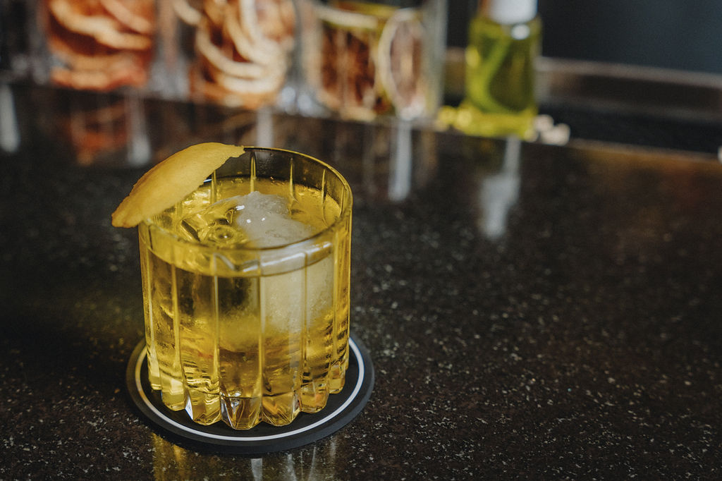 a glass of yellow liquid with a slice of lemon on top of it