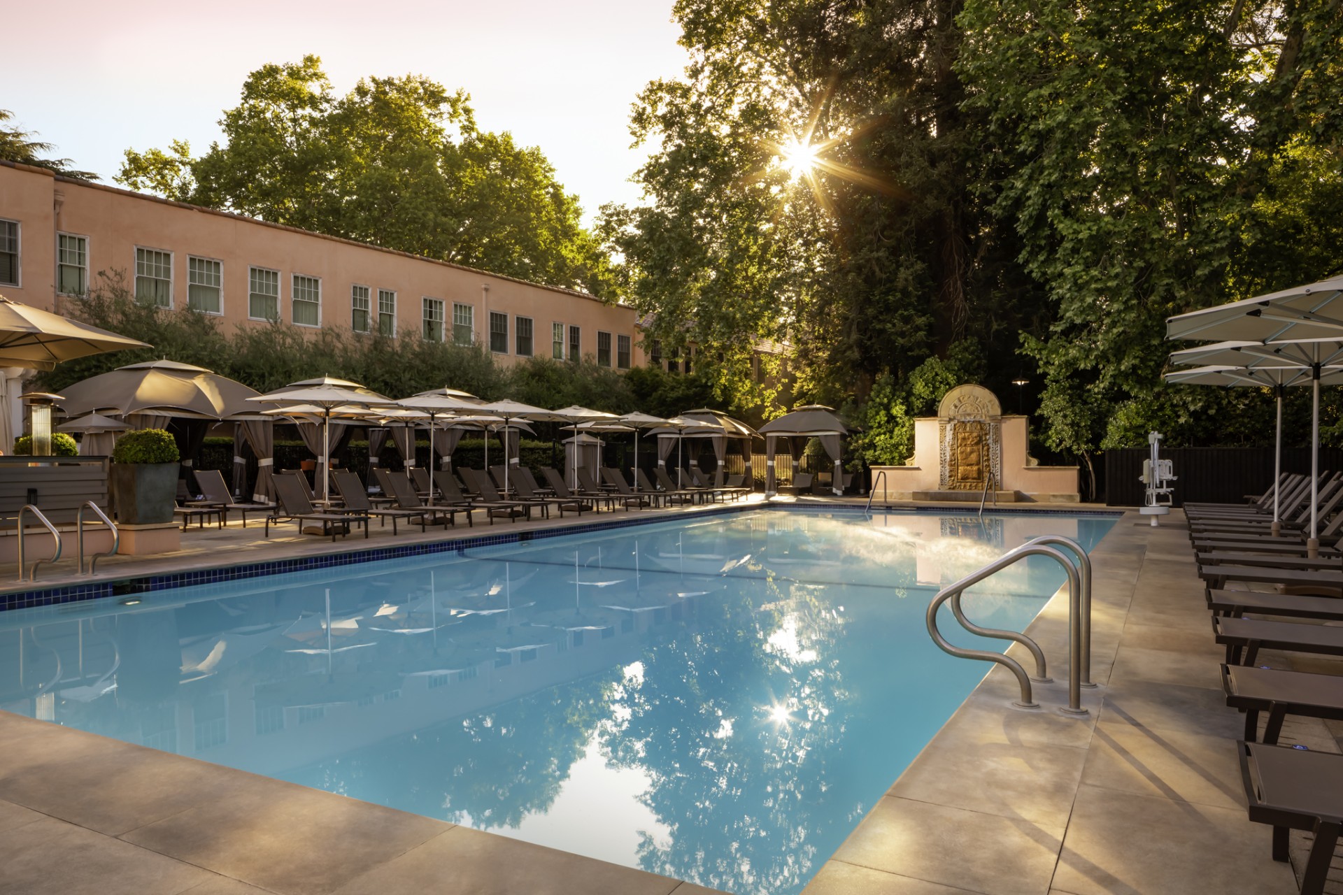a pool with umbrellas and chairs in front of a building