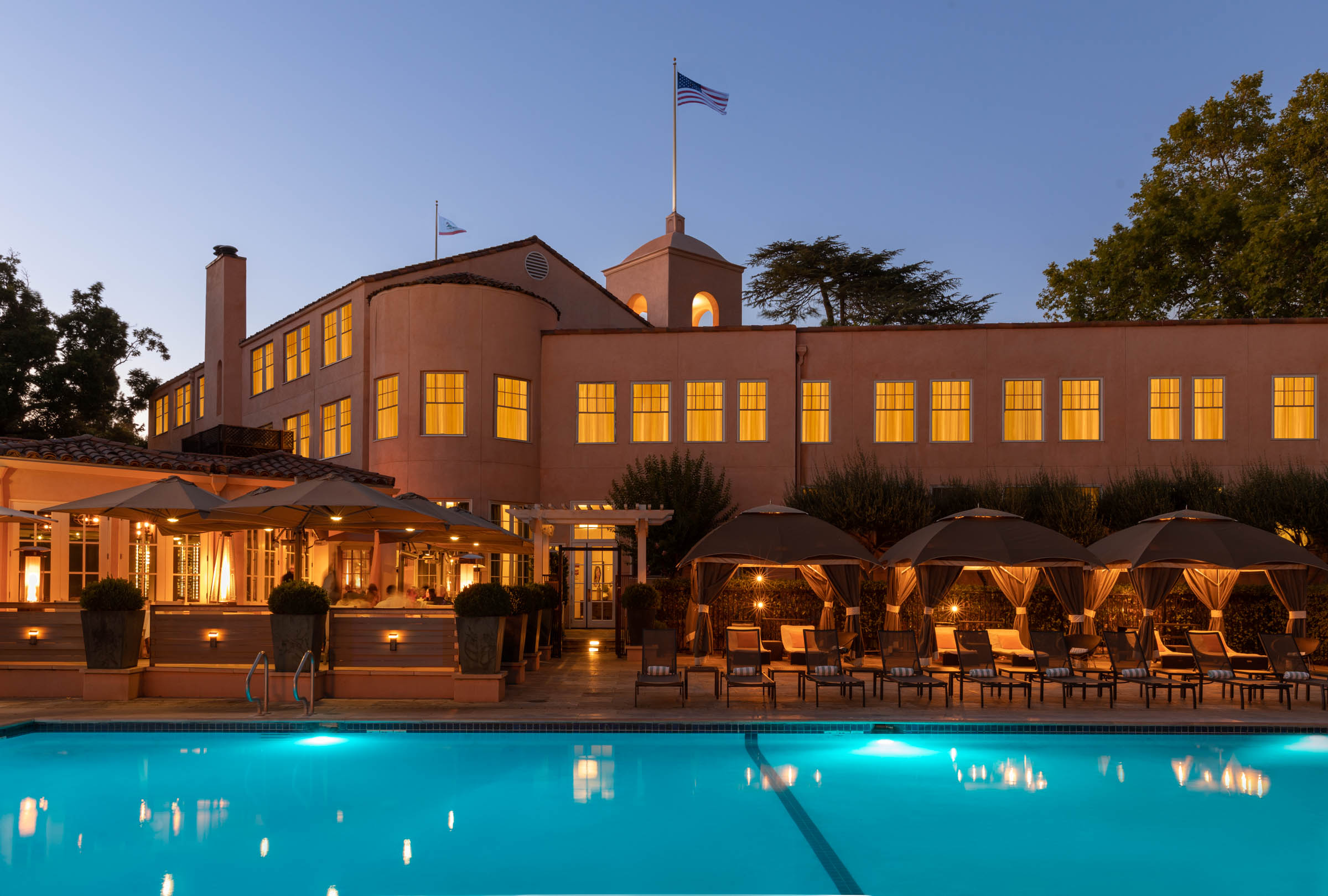 a pool with umbrellas and chairs in front of a building