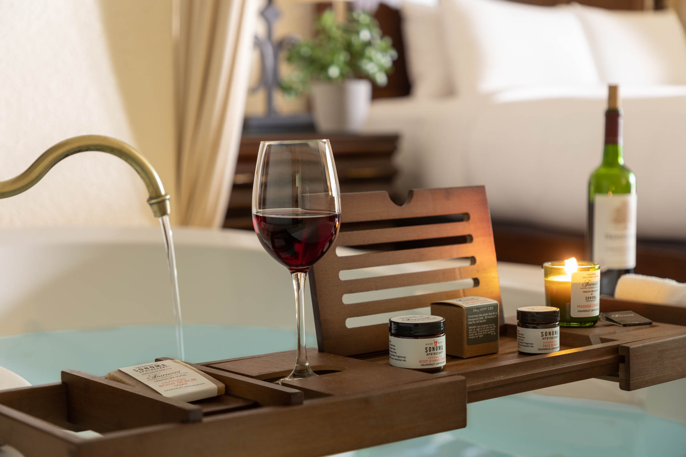 a glass of wine on a tray with candles and a bathtub